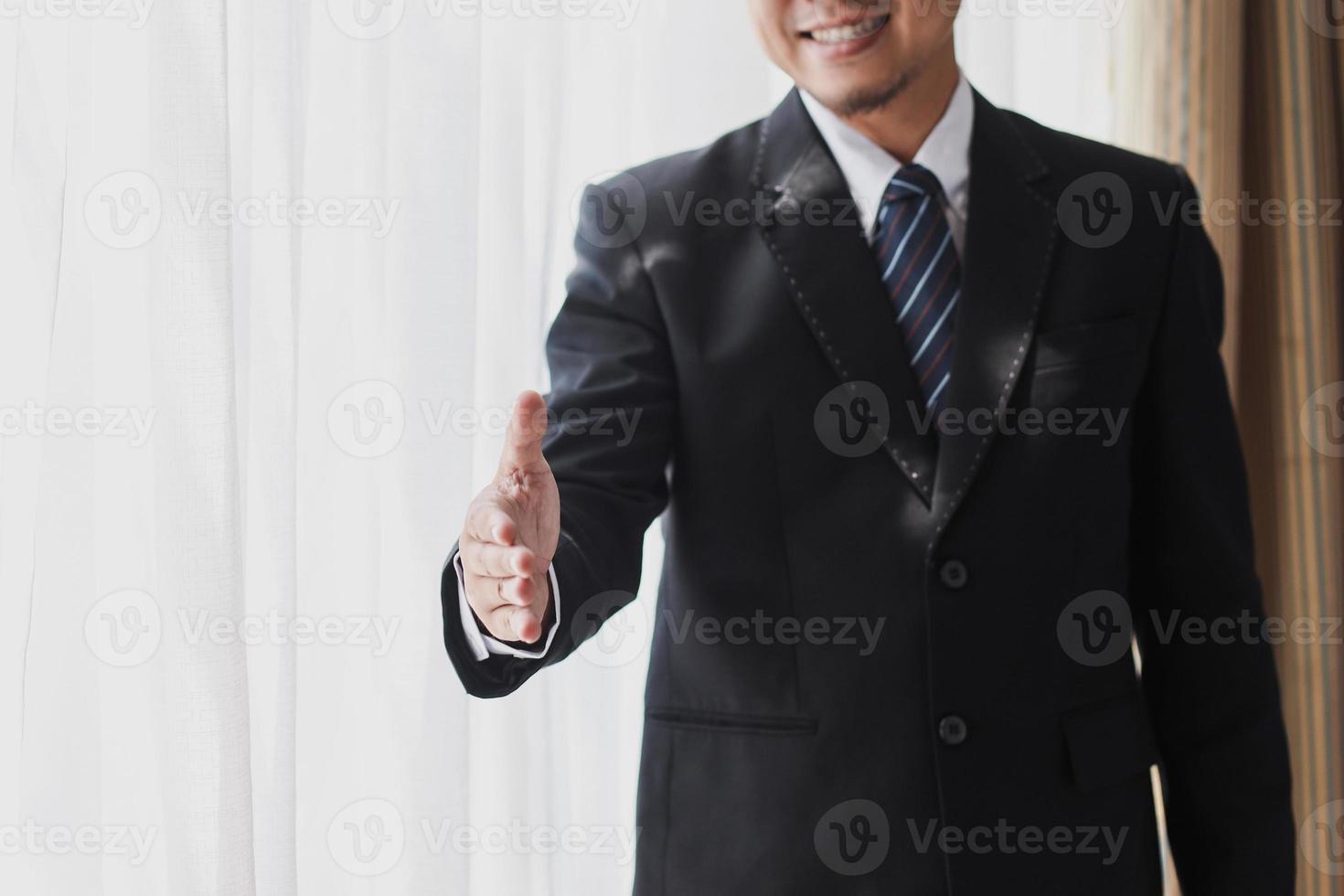 Cropped shot of Businessman in black suit and tie extending hand for hand shake photo
