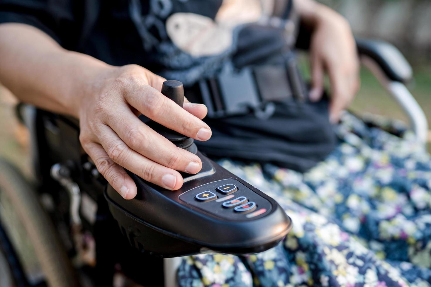 mujer asiática paciente en silla de ruedas eléctrica con joystick y control remoto en la sala del hospital de enfermería, concepto médico fuerte y saludable foto