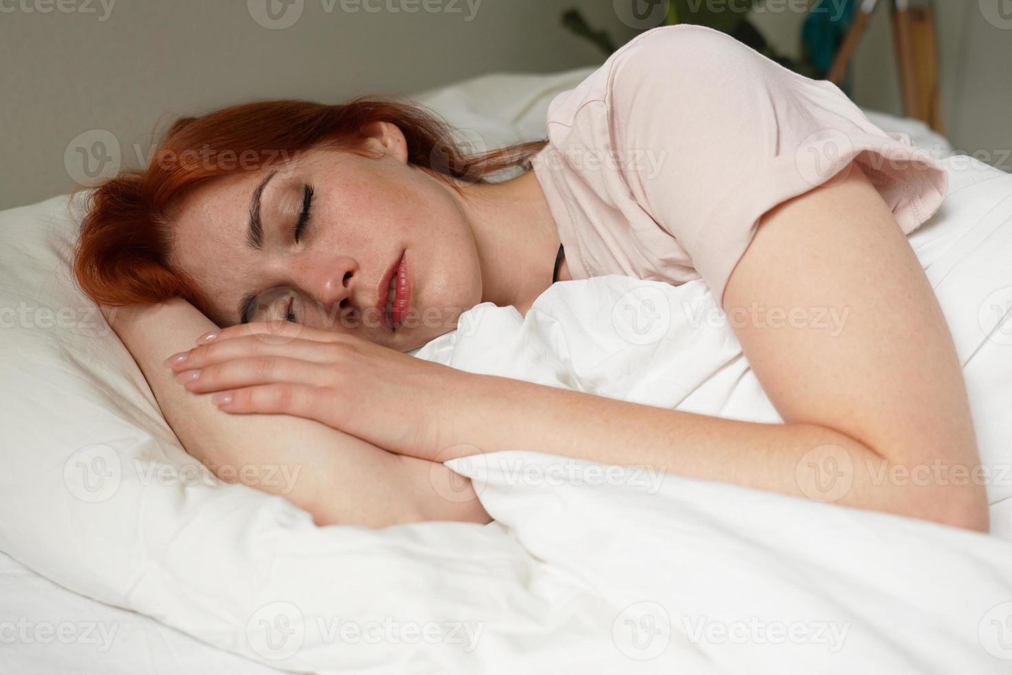 young woman in bed sleeping or napping during daytime photo