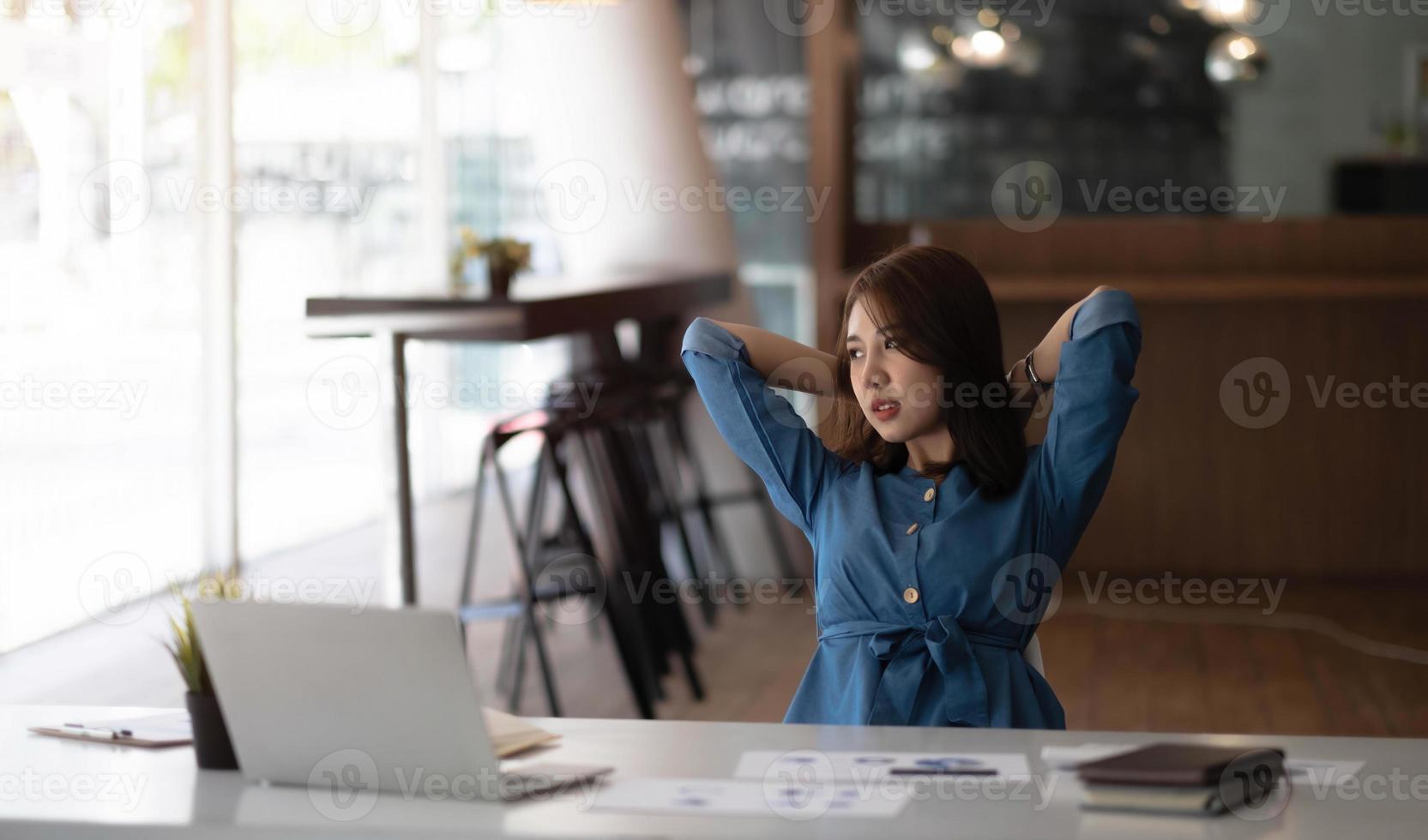 Asian woman enjoy and happy of relaxing at the office. Hold hands behind head concept of success future. photo