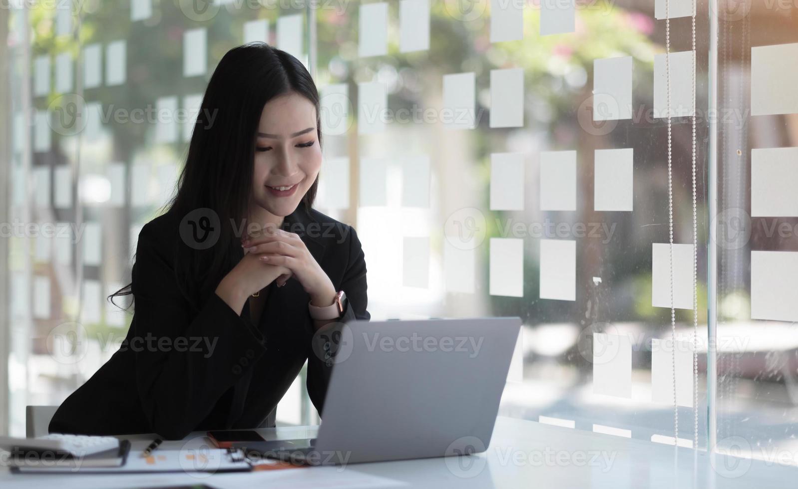 Charming asian businesswoman sitting working on laptop in office. photo