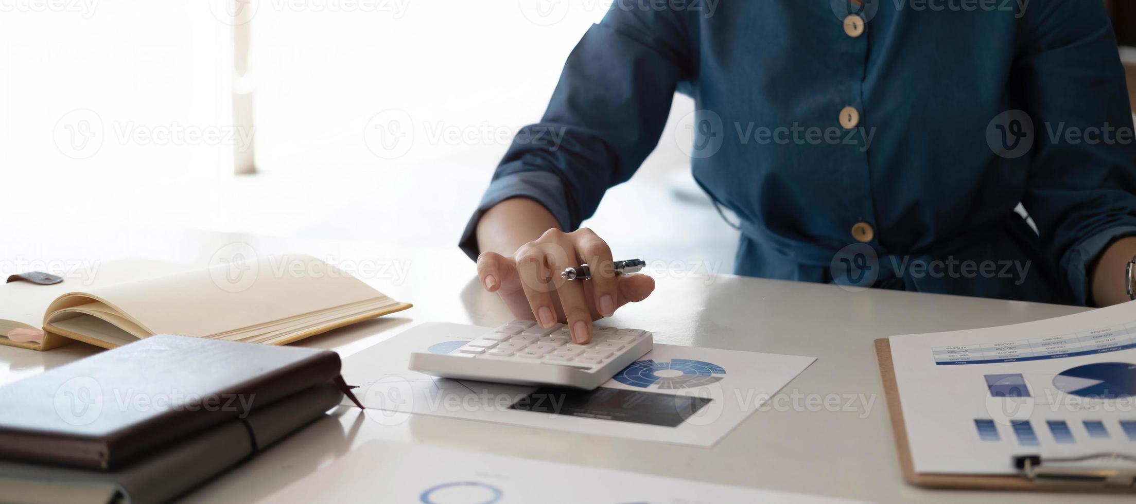 Close up woman hand using calculator and working with laptop calculate about finance accounting at coffeeshop outdor.finance accounting concept photo