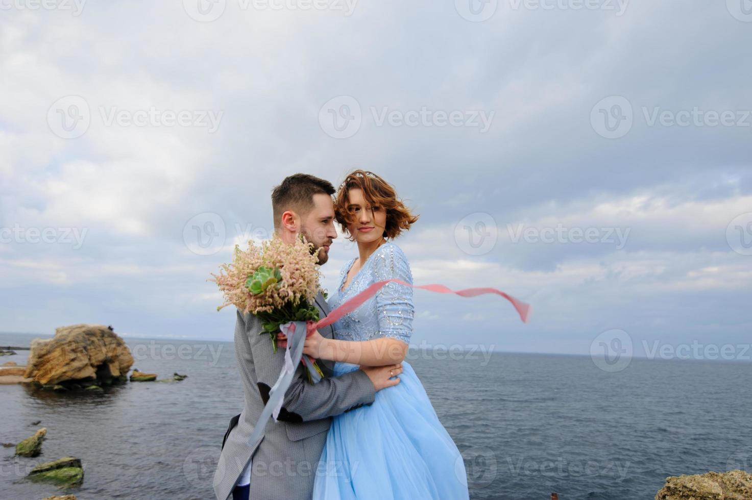 Wedding photo session of a couple on the seashore. Blue wedding dress on the bride.