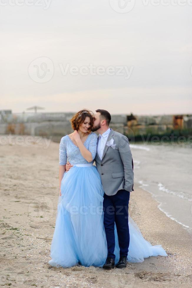 Wedding photo session of a couple on the seashore. Blue wedding dress on the bride.