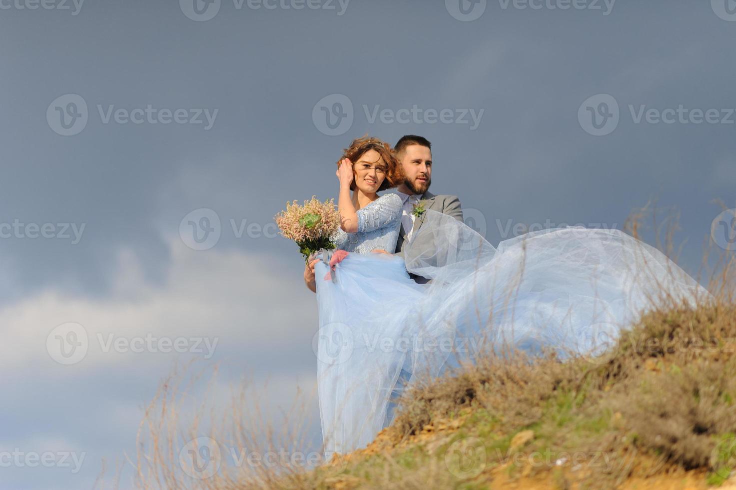 Wedding photo session of a couple on the seashore. Blue wedding dress on the bride.