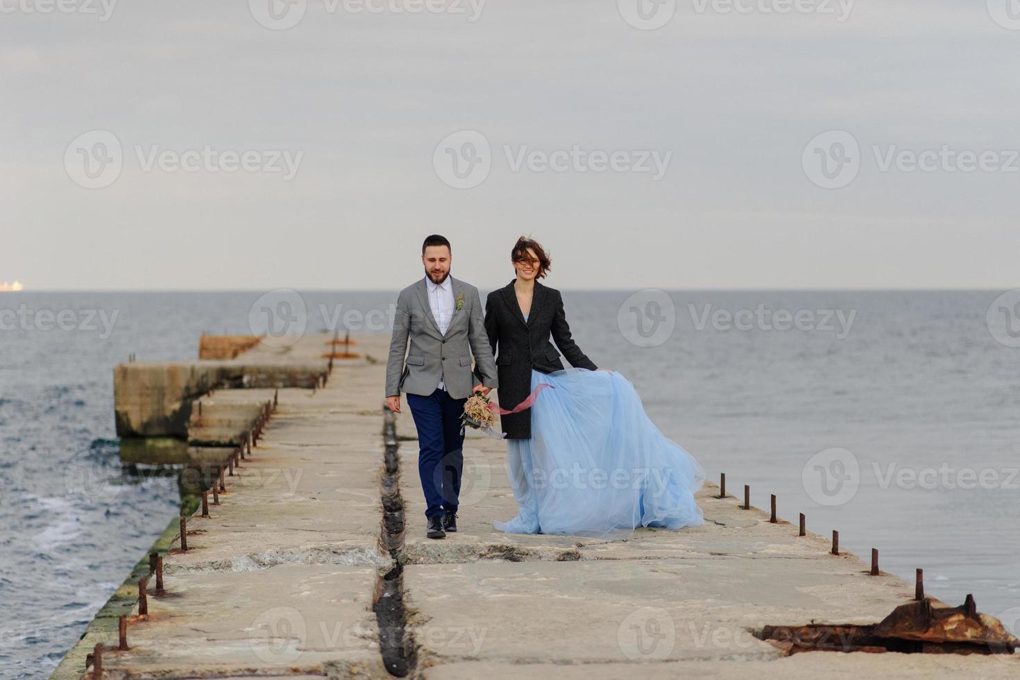 Wedding photo session of a couple on the seashore. Blue wedding dress on the bride.