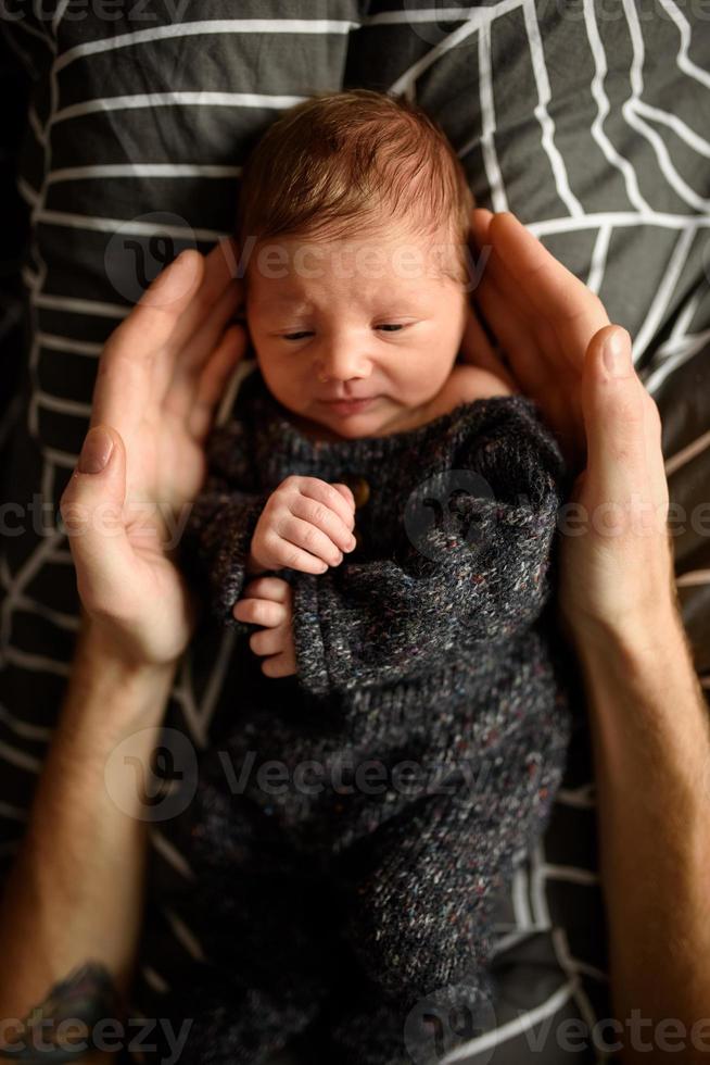 un niño recién nacido está mirando la ventana de su cuna. un niño nacido a los 8 meses de gestación. hay un traje de punto en el niño. foto