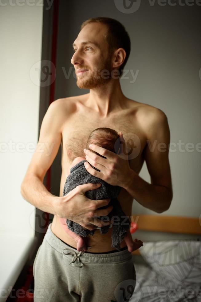 A father holds in his arms his newborn son. photo