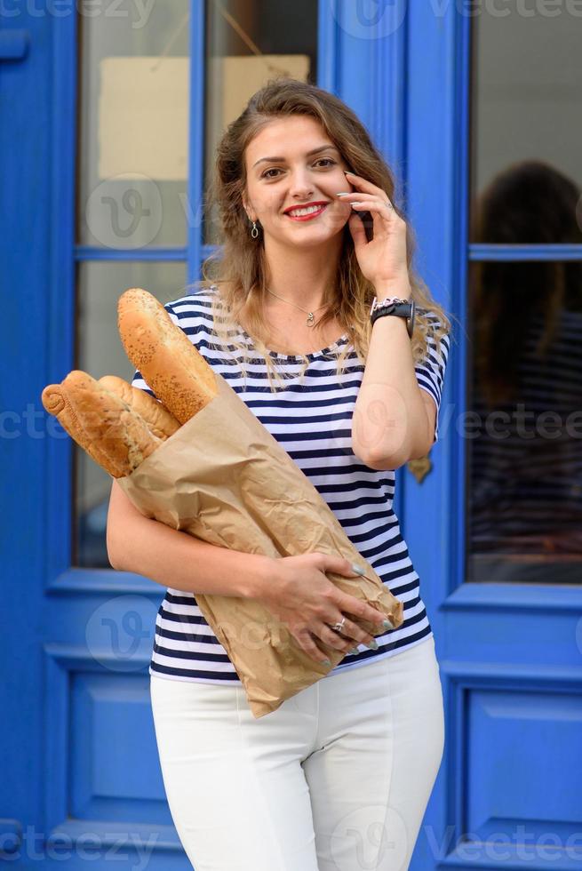 Young beautiful woman posing with a baguette in her hands on the streets of France. photo