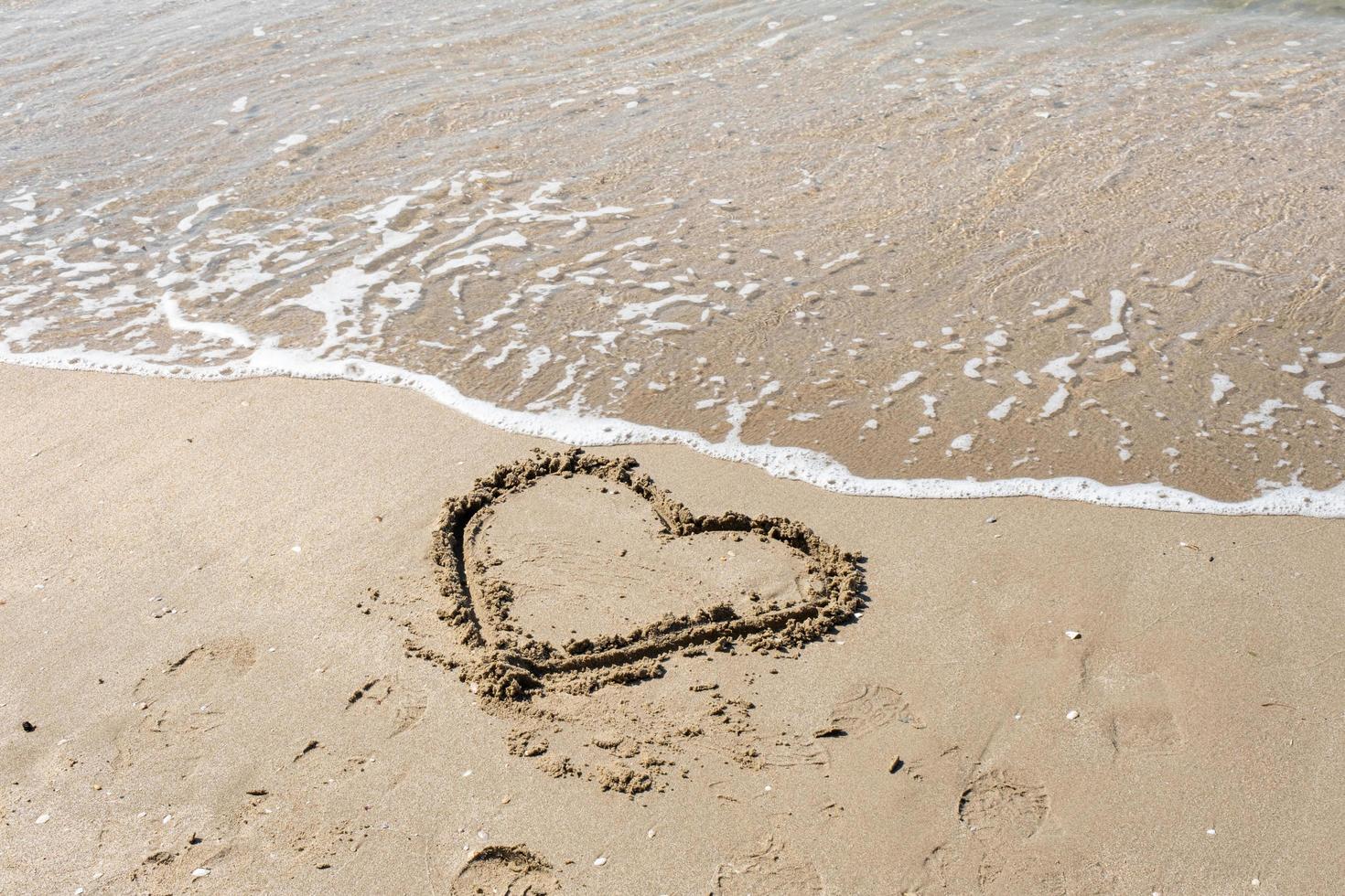 A drawing of a heart on a yellow sand at a beautiful seascape background. Horizontal composition. photo