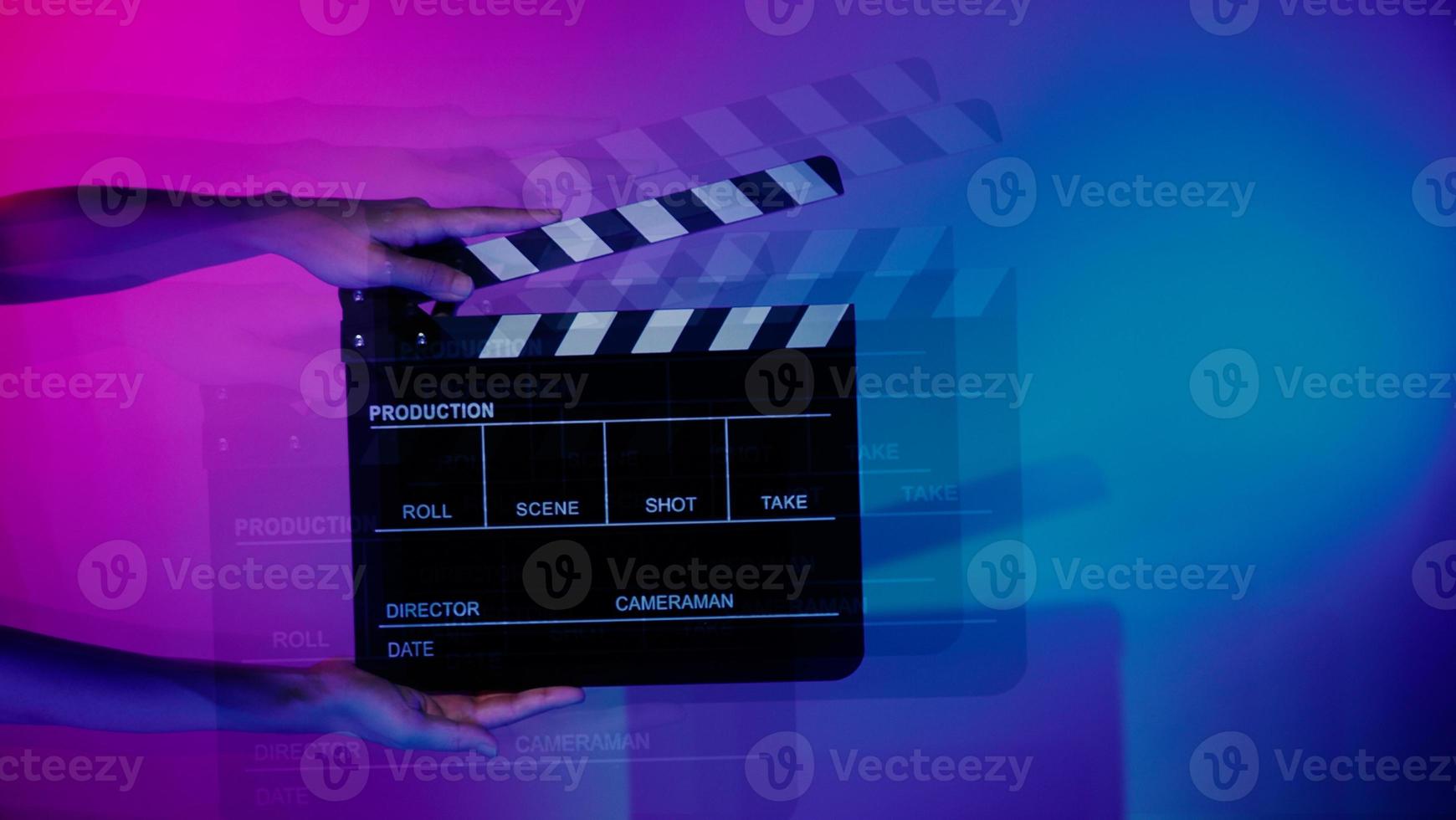 Hand holds empty film making clapperboard on color background in studio photo