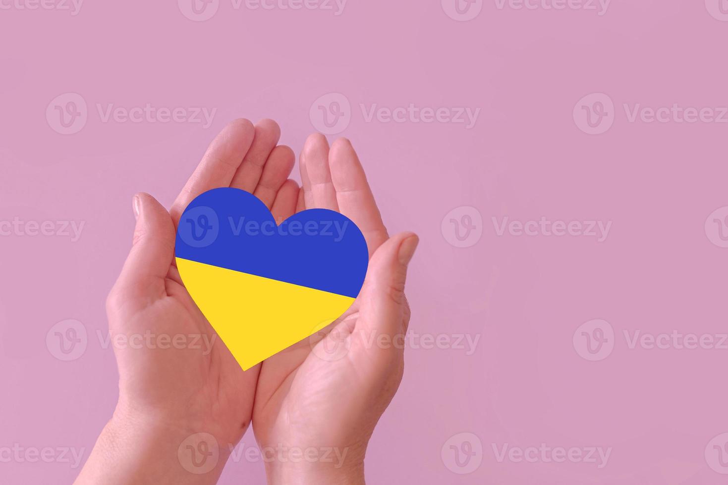 Me encanta el corazón azul y amarillo en las manos con un fondo colorido. concepto de ucrania foto