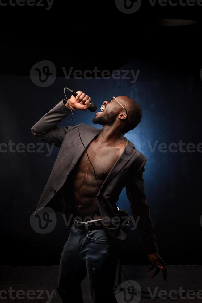 A black African American is emotionally singing into a microphone. Close-up studio portrait. photo