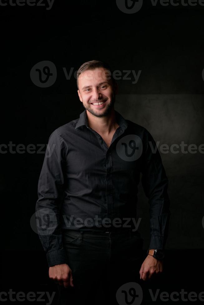 Studio portrait of a young caucasian man in a black blazer, looking at the camera, standing against plain studio background photo