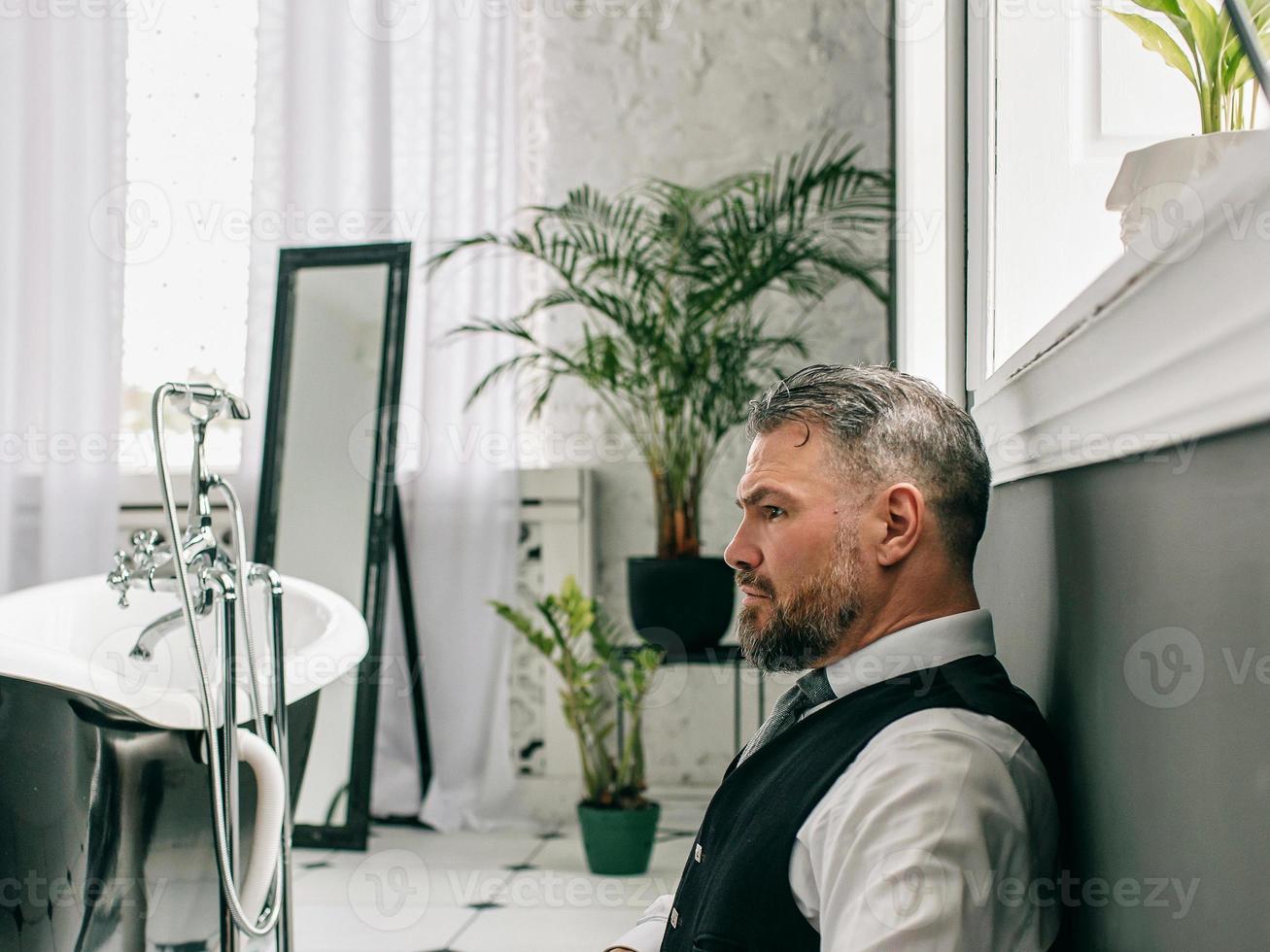 handsome mature courageous  stylish scotsman businessman in kilt and suit in bathroom. Style, work from home, fashion, lifestyle, culture, ethnic concept. photo