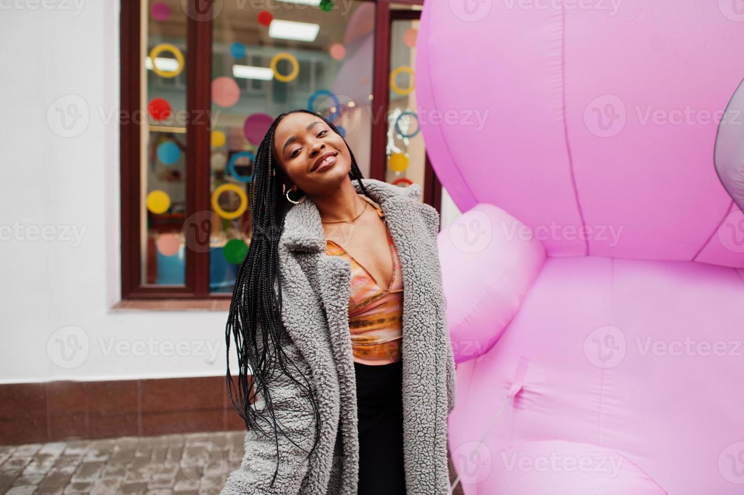 señora milenaria afroamericana cerca de oso de peluche rosa inflable. foto