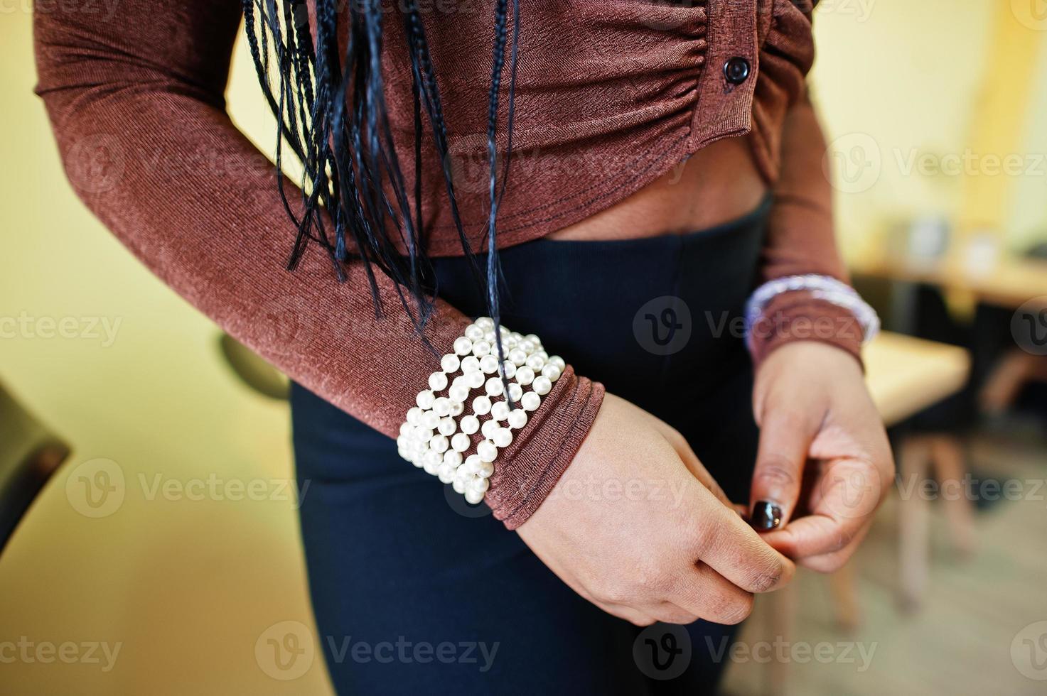 manos de mujer afroamericana con cadena de pulsera atada a la muñeca de la mujer. foto