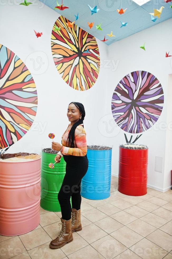 African american millennial lady at candy shop with lolipops. photo