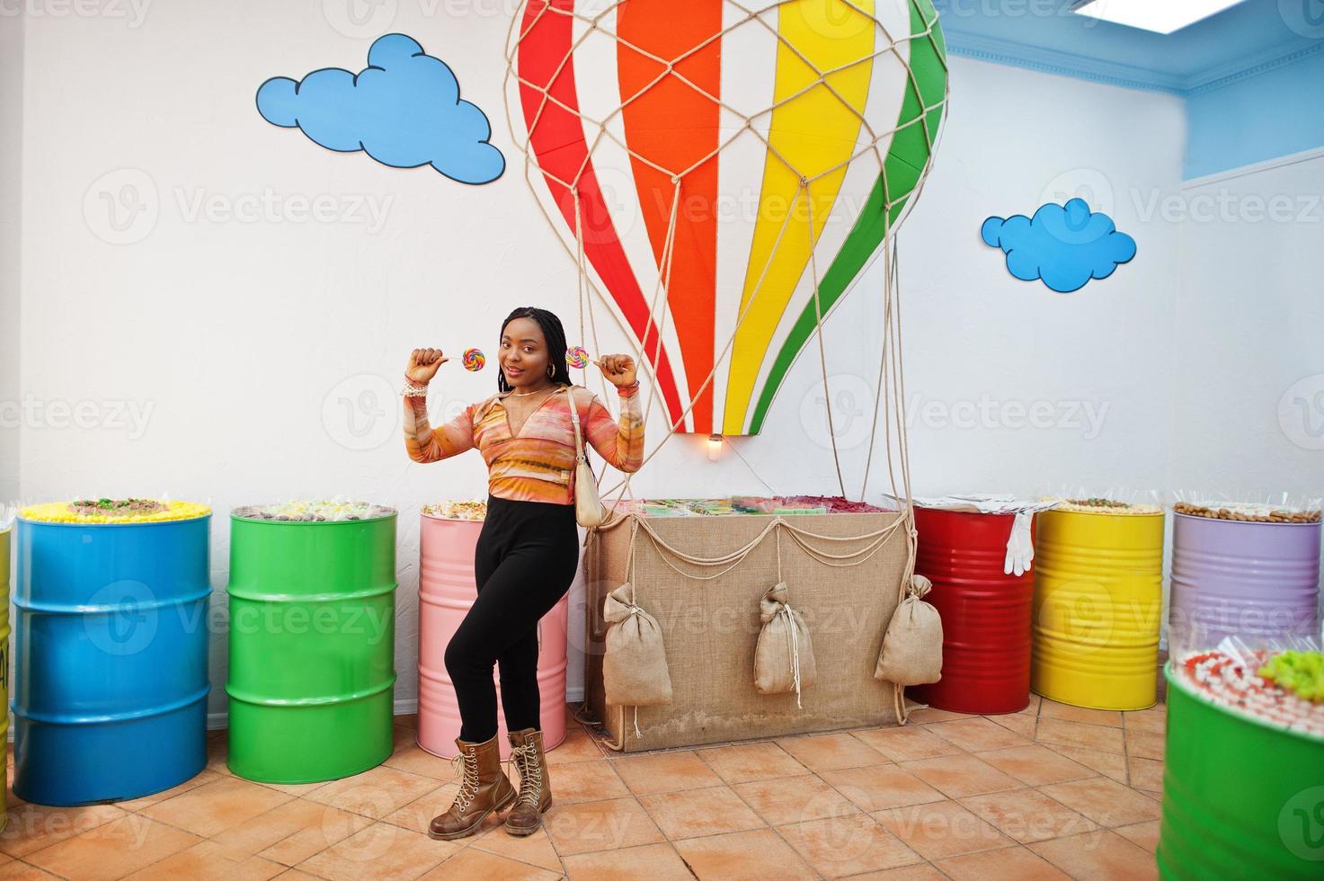 African american millennial lady at candy shop with lolipops. photo