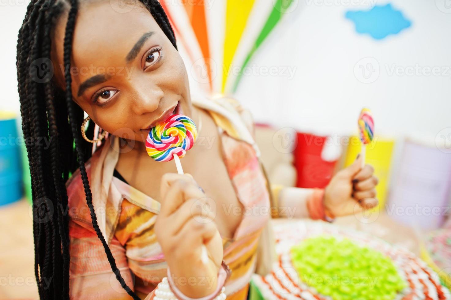 dama milenaria afroamericana en la tienda de dulces con piruletas. foto