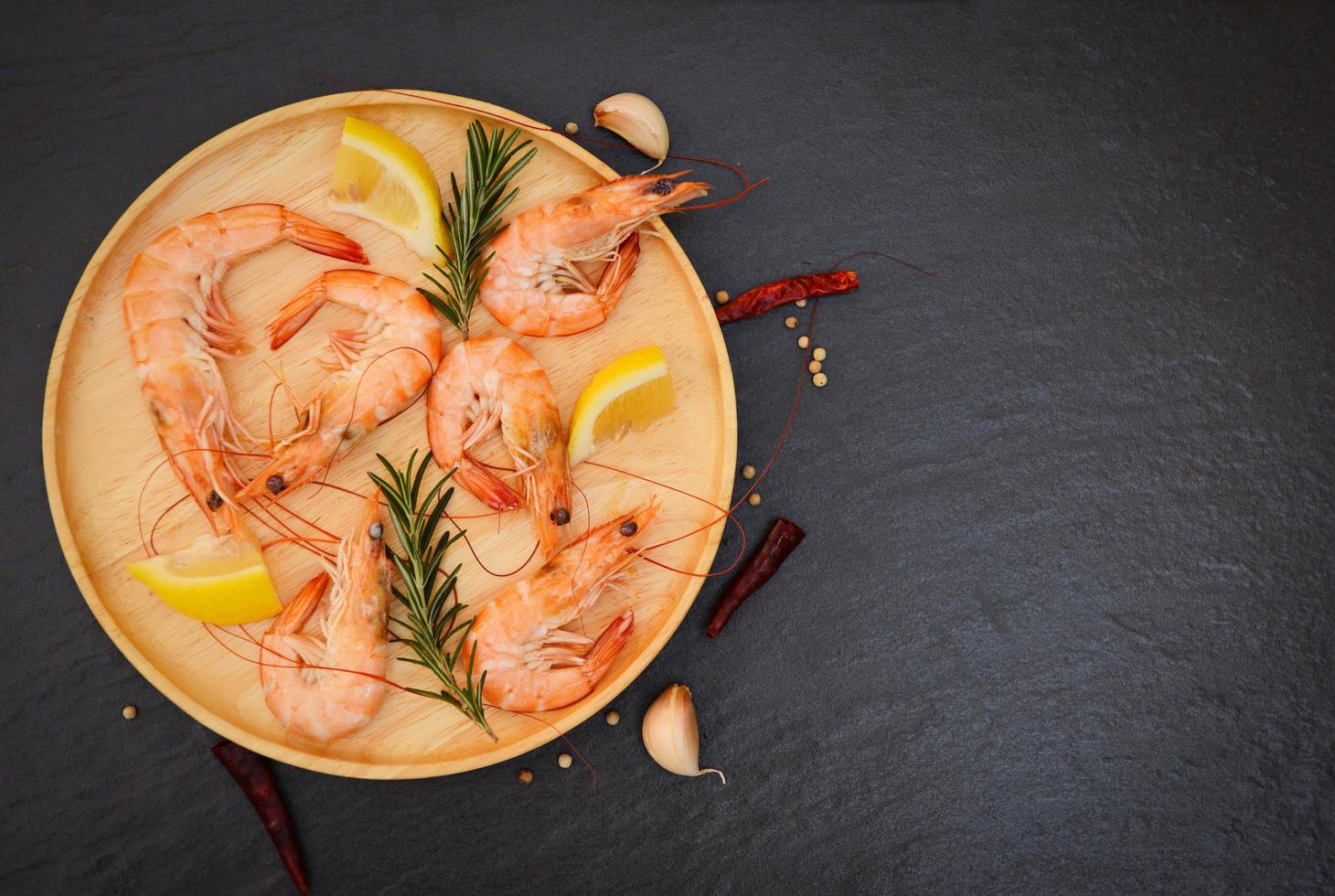 Fresh shrimps served on wooden plate with rosemary lemon , boiled peeled shrimp prawns cooked in the seafood restaurant - top view photo
