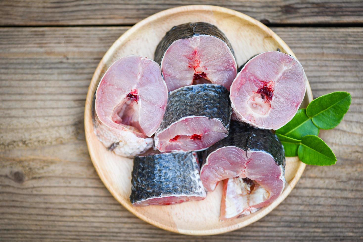 Snakehead fish for cooking food, striped snakehead fish chopped with ingredients kaffir lime leaves on plate and wooden table kitchen background, Fresh raw Snake head fish menu freshwater fish photo