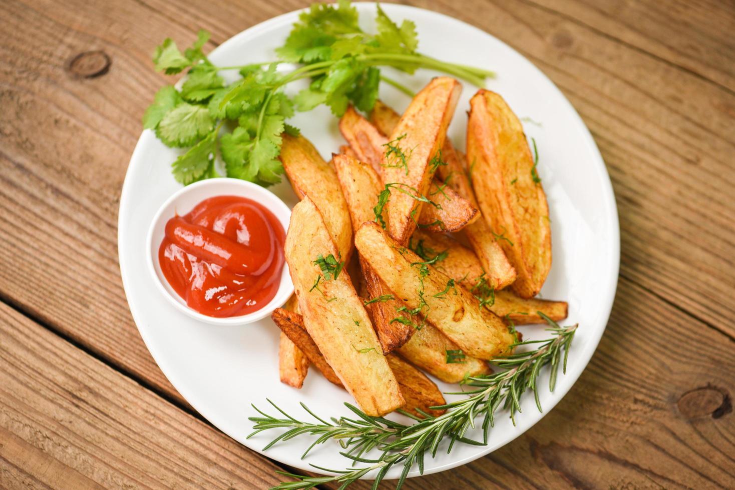 gajos de patata en un plato blanco con cilantro de hierbas de romero y salsa de ketchup de tomate, cocinando patatas fritas o patatas fritas foto