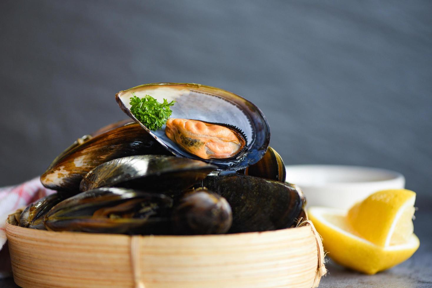 mariscos frescos en el restaurante comida de concha de mejillón en vapor de bambú - mejillones con hierbas limón sobre fondo de comida de vapor de cocina foto