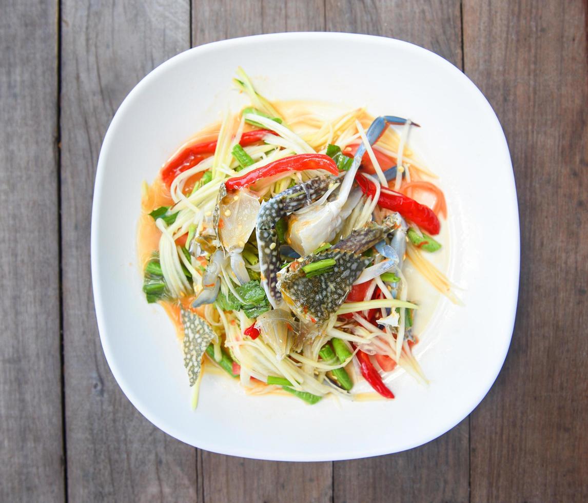 Papaya salad with blue crab Thai food raw crab spicy salad seafood and vegetable on wooden table photo
