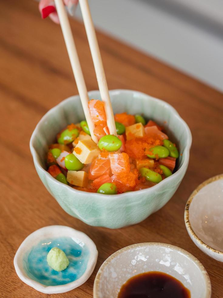 Mix sushi donburi in a small bowl , Japanese food. Focus on food at the chopsticks. photo