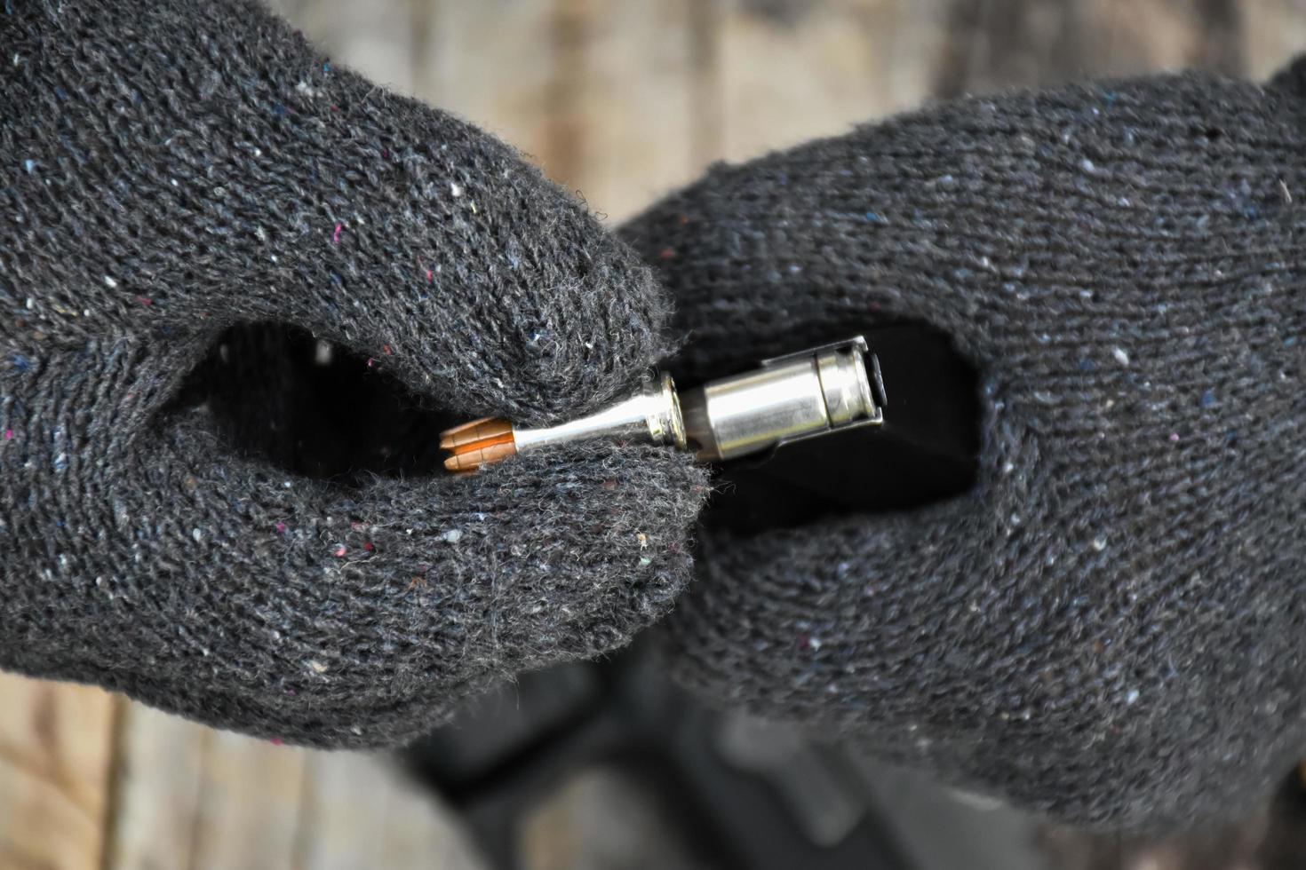 Two hands reloading 9mm bullets full metal jacket rounds into a black magazine. Soft and selective focus on bullets. photo