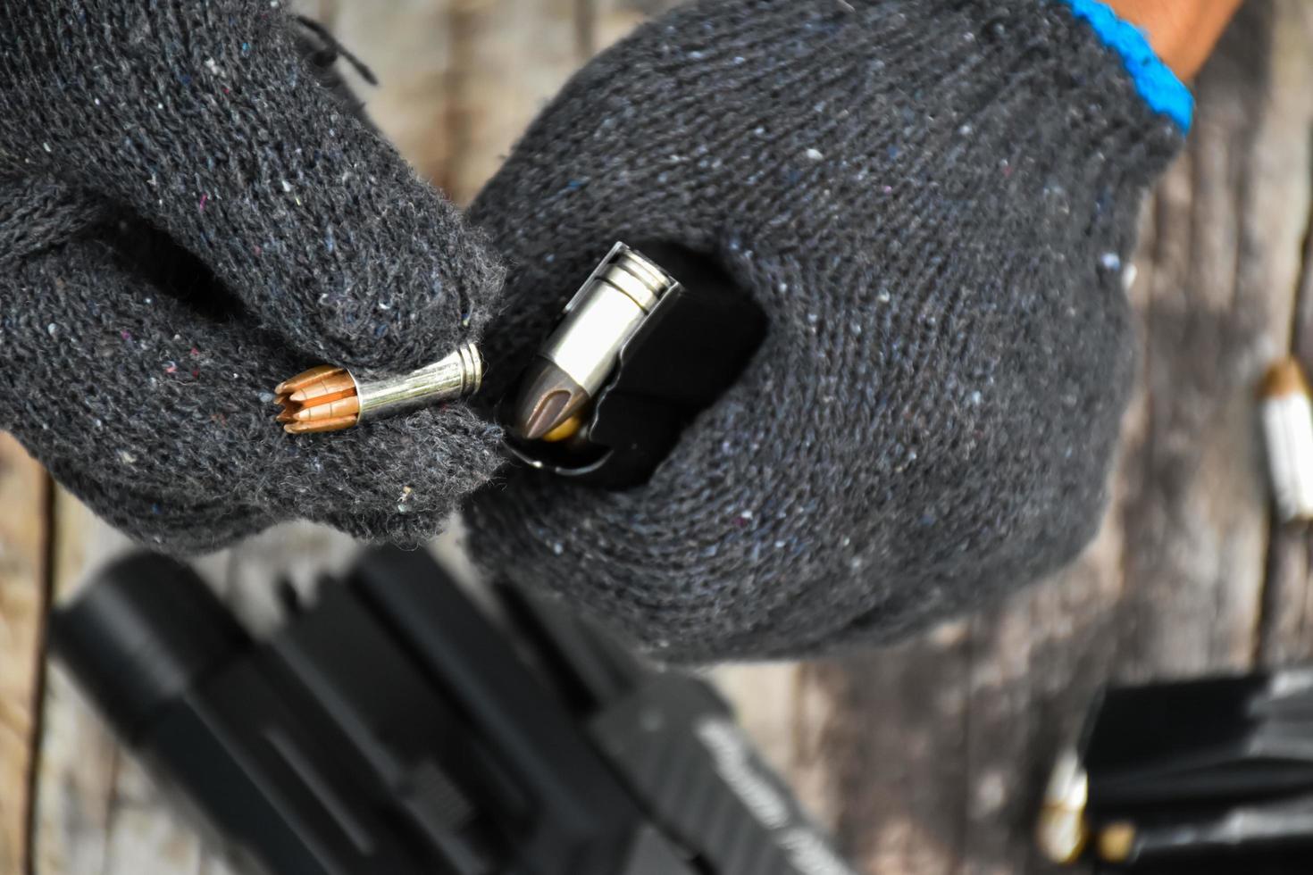 Two hands reloading 9mm bullets full metal jacket rounds into a black magazine. Soft and selective focus on bullets. photo