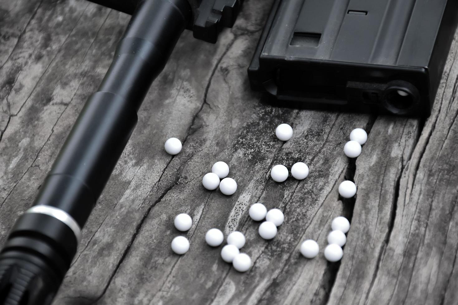 primer plano de balas de plástico blanco de pistola airsoft o pistola bb en suelo de madera, enfoque suave y selectivo en balas blancas. foto