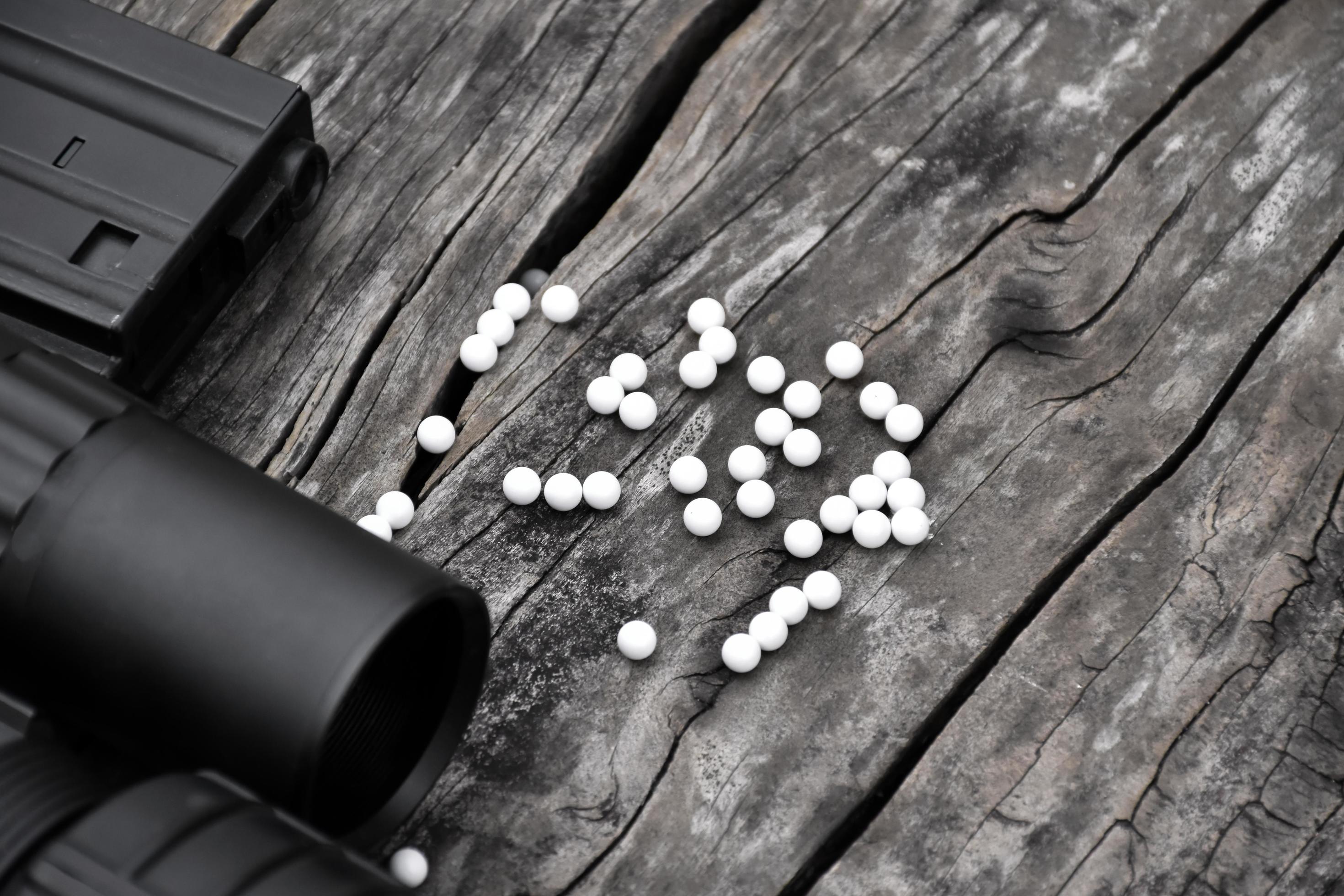 Closeup of white plastic bullets of airsoft gun or bb gun on wooden