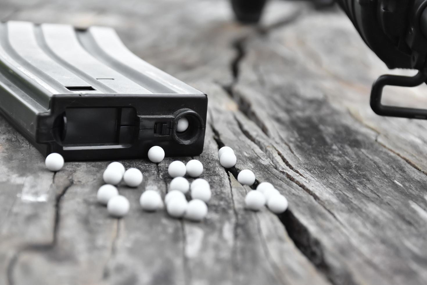 Closeup of white plastic bullets of airsoft gun or bb gun on wooden floor, soft and selective focus on white bullets. photo