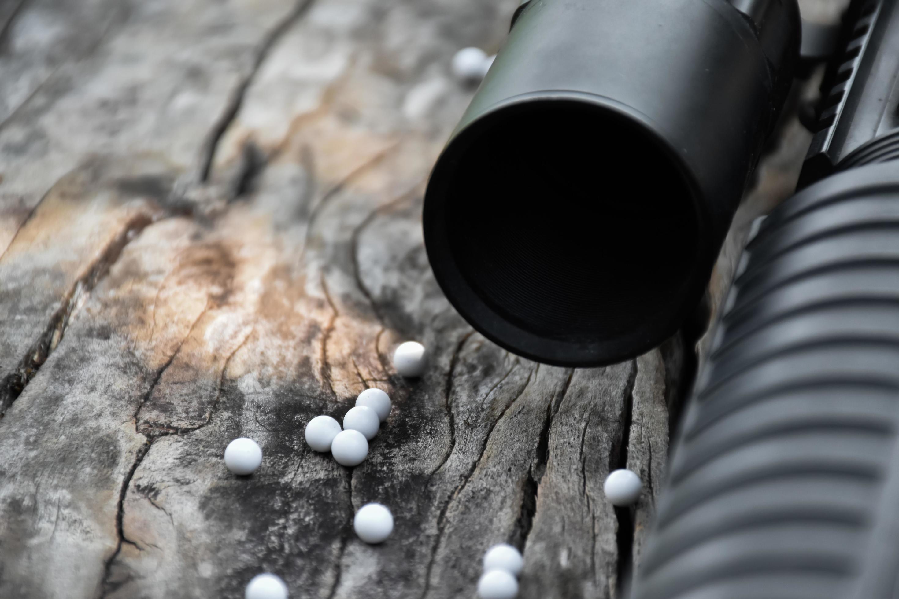 Closeup of white plastic bullets of airsoft gun or bb gun on wooden