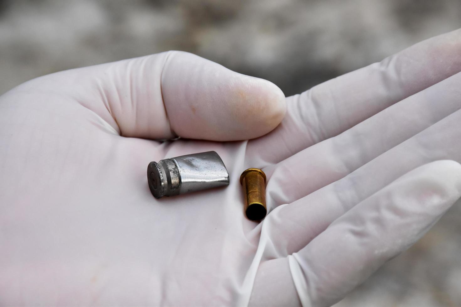 Forensic officers holds physical evidence which is the bullet shell up to eye level to determine the size and type of ammunition at the murder. photo