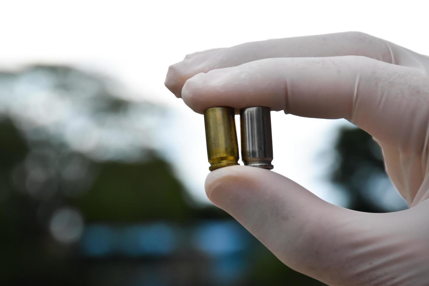 Forensic officers holds physical evidence which is the bullet shell up to eye level to determine the size and type of ammunition at the murder. photo