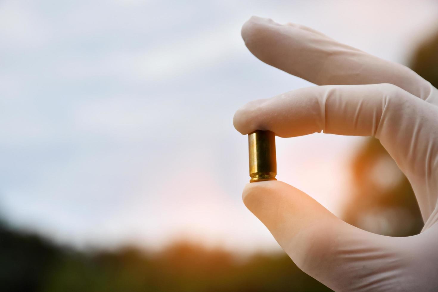 Forensic officers holds physical evidence which is the bullet shell up to eye level to determine the size and type of ammunition at the murder. photo