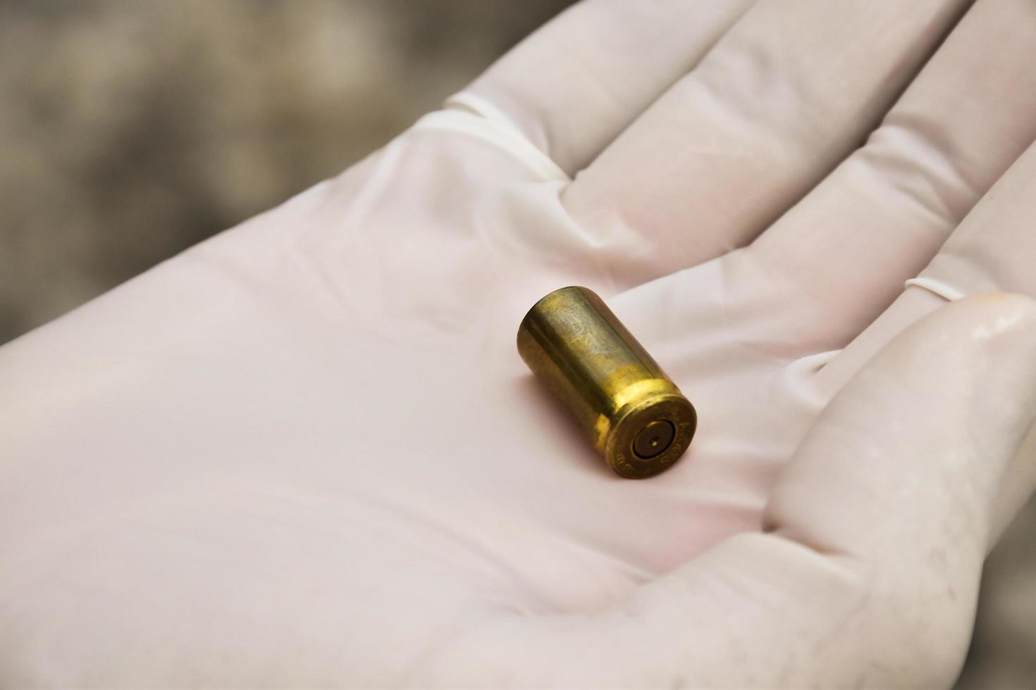 Forensic officers holds physical evidence which is the bullet shell up to eye level to determine the size and type of ammunition at the murder. photo