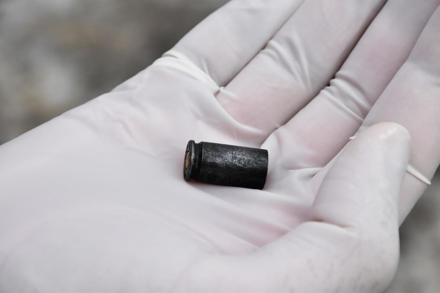 Forensic officers holds physical evidence which is the bullet shell up to eye level to determine the size and type of ammunition at the murder. photo