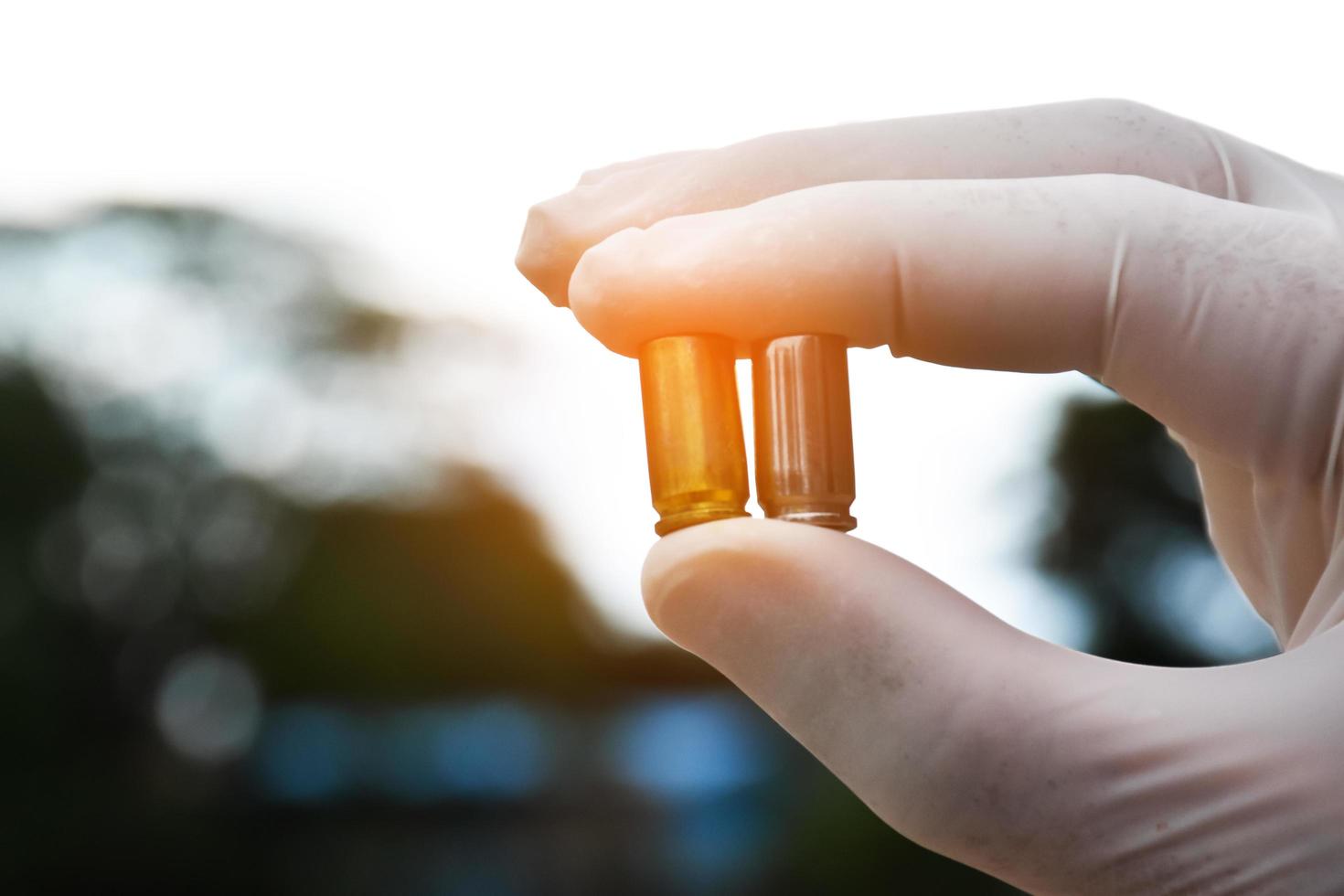 Forensic officers holds physical evidence which is the bullet shell up to eye level to determine the size and type of ammunition at the murder. photo