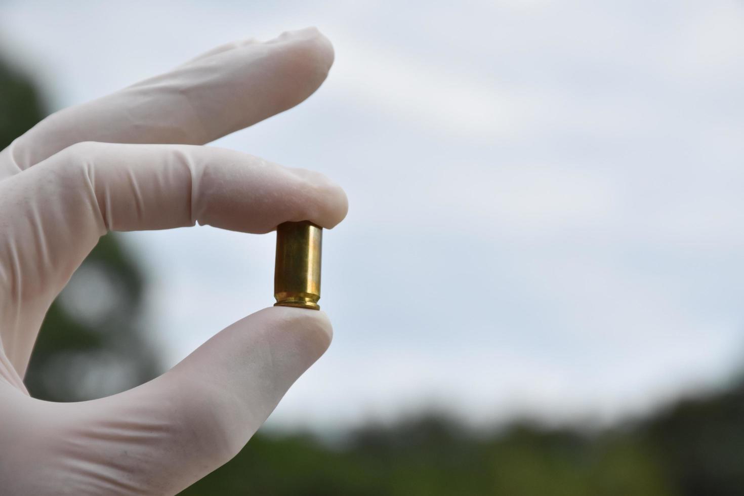 Forensic officers holds physical evidence which is the bullet shell up to eye level to determine the size and type of ammunition at the murder. photo