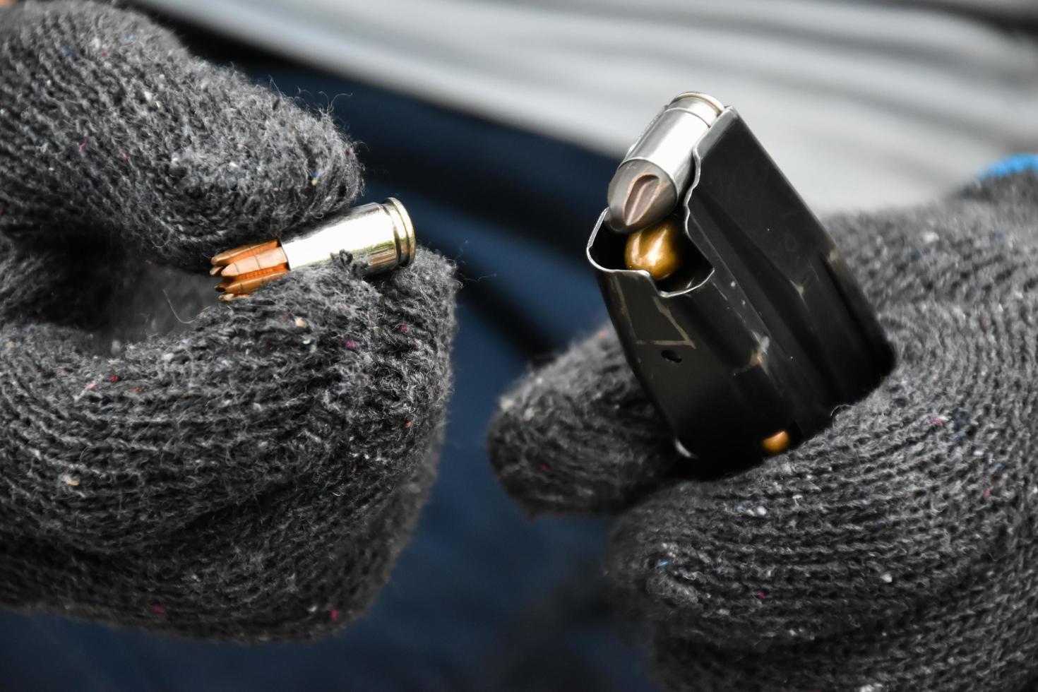 Two hands reloading 9mm bullets full metal jacket rounds into a black magazine. Soft and selective focus on bullets. photo