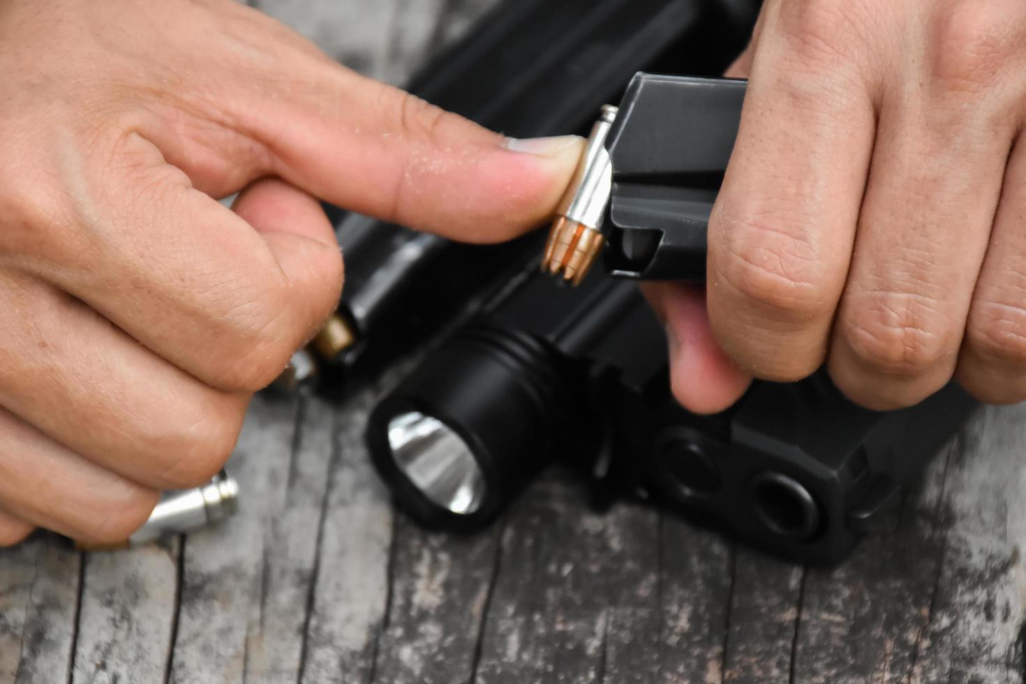 Two hands reloading 9mm bullets full metal jacket rounds into a black magazine. Soft and selective focus on bullets. photo