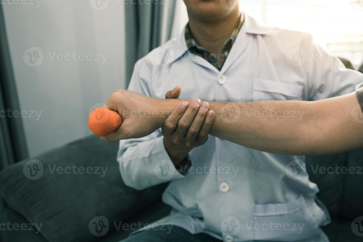 Fisioterapeuta masculino joven asiático que ayuda al paciente con ejercicios de levantamiento de pesas en el consultorio. foto