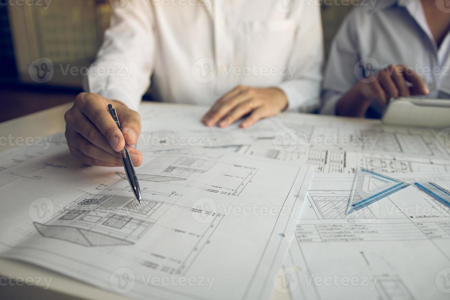 Architects engineer working with blueprints on table and discussing project together at the meeting in the office. photo