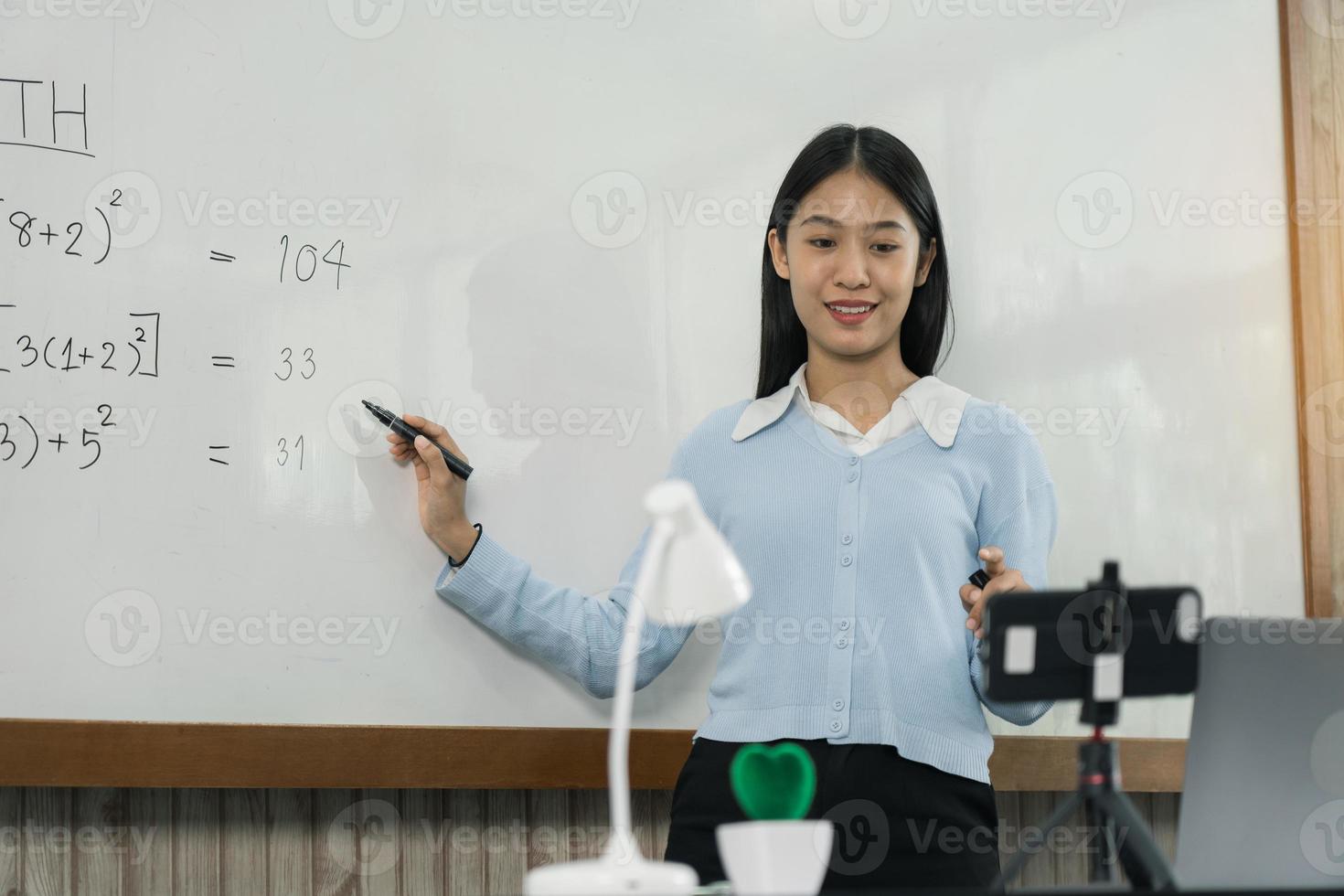 profesor explicando los números en la pizarra mientras hace videollamadas con estudiantes que estudian en línea. foto