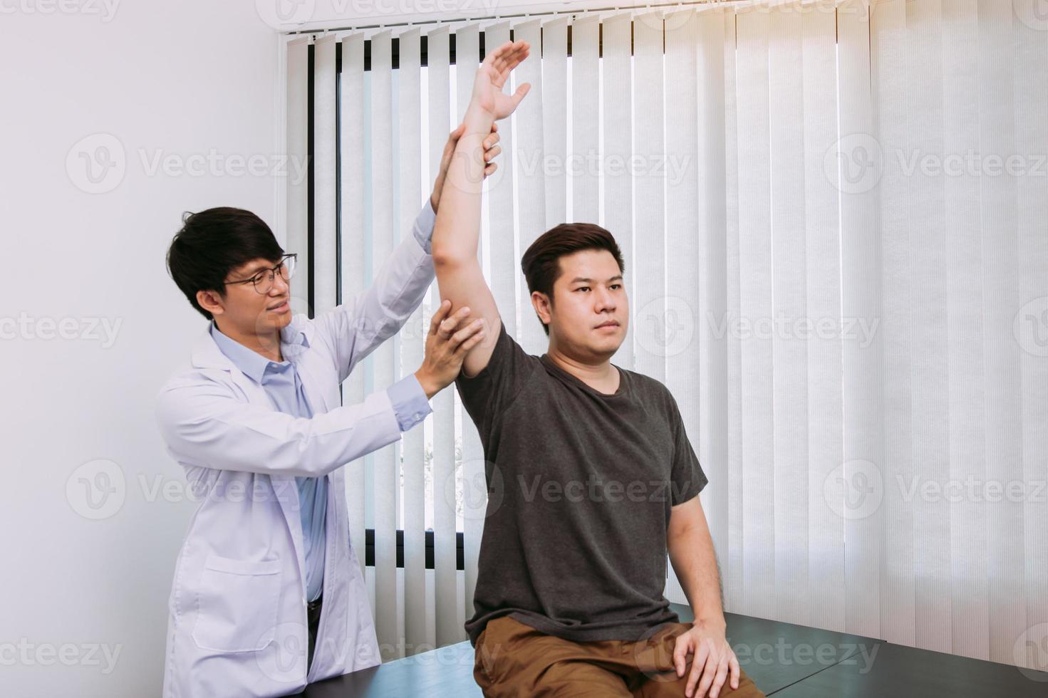 Chiropractor stretching a young man arm in medical office photo