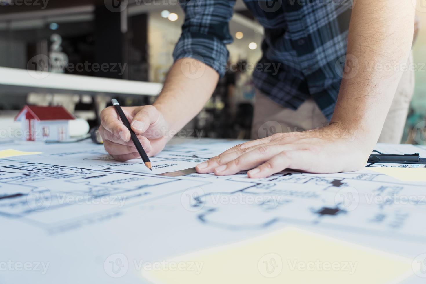 Interior designer or architect reviewing blueprints and holding pencil drawing on desk at home office. photo